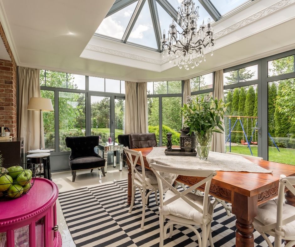 A furnished sunroom overlooking a swingset in the back yard